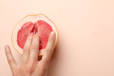 Woman touching half of grapefruit on beige background, top view and space for text. Sex concept