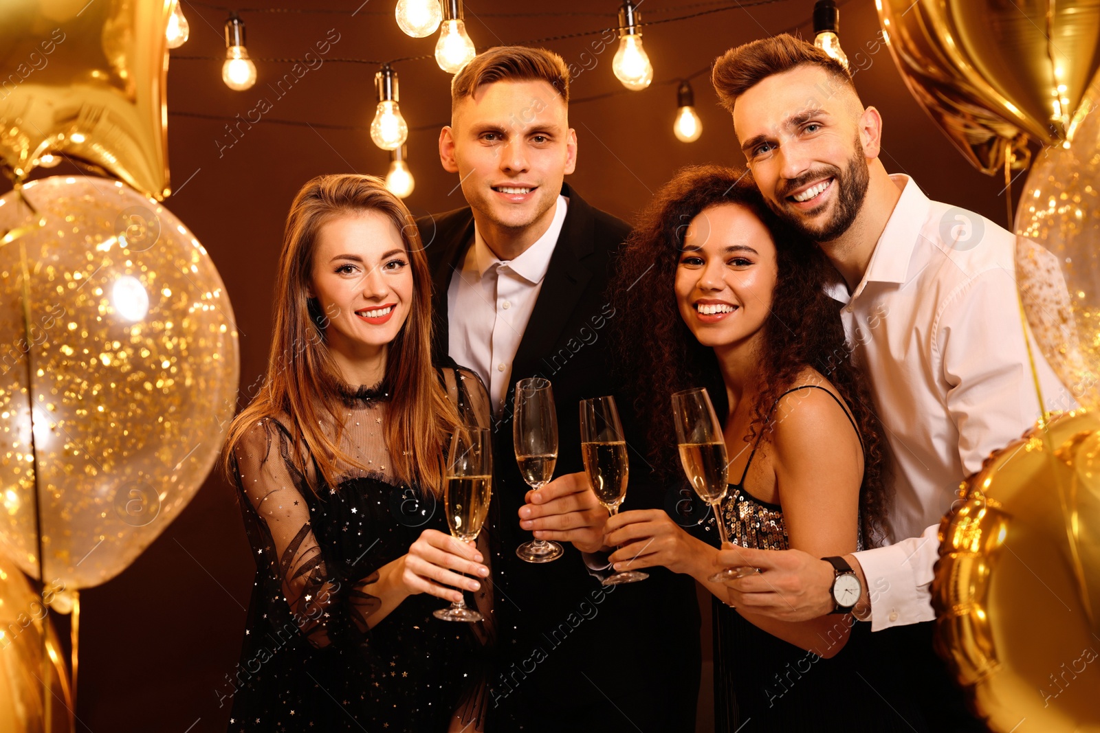 Photo of Happy friends with glasses of sparkling wine celebrating New Year indoors