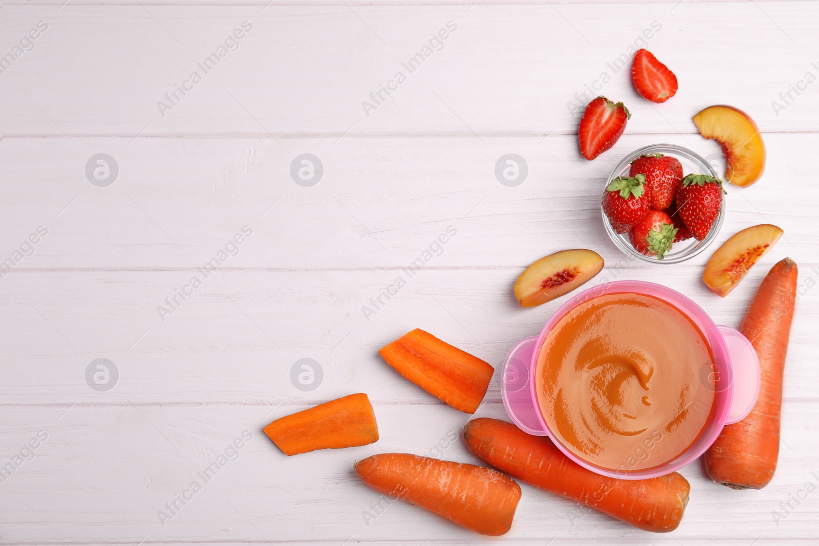 Photo of Baby food in bowl and fresh ingredients on pink wooden table, flat lay. Space for text