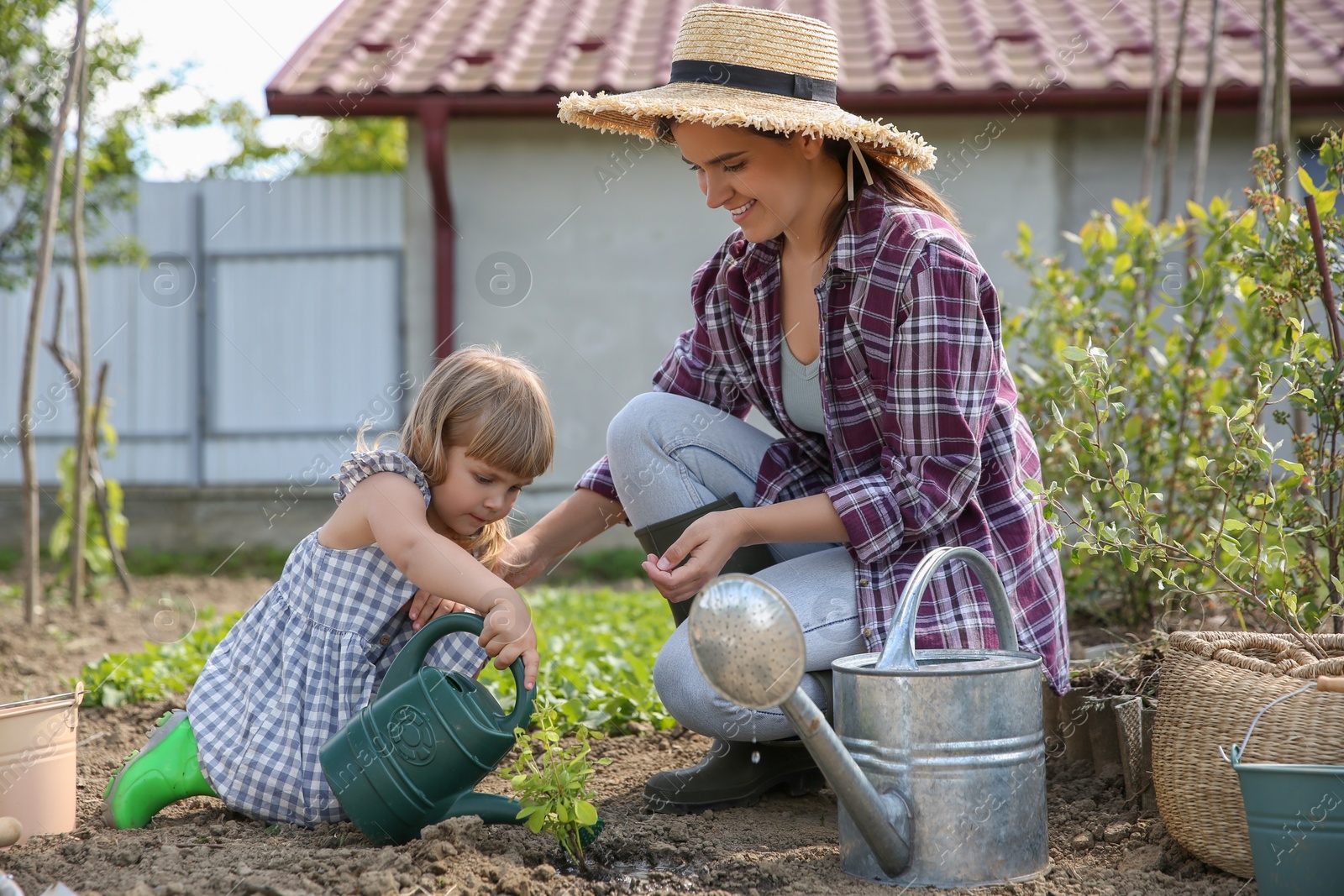 Photo of Mother and her cute daughter planting tree together in garden