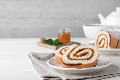 Photo of Tasty cake roll with jam on white wooden table, space for text