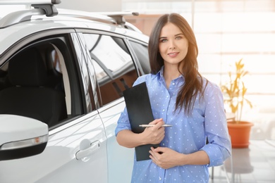 Photo of Saleswoman with clipboard in salon. Buying new car