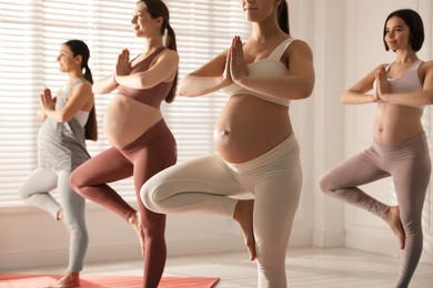 Photo of Group of pregnant women practicing yoga in gym, closeup