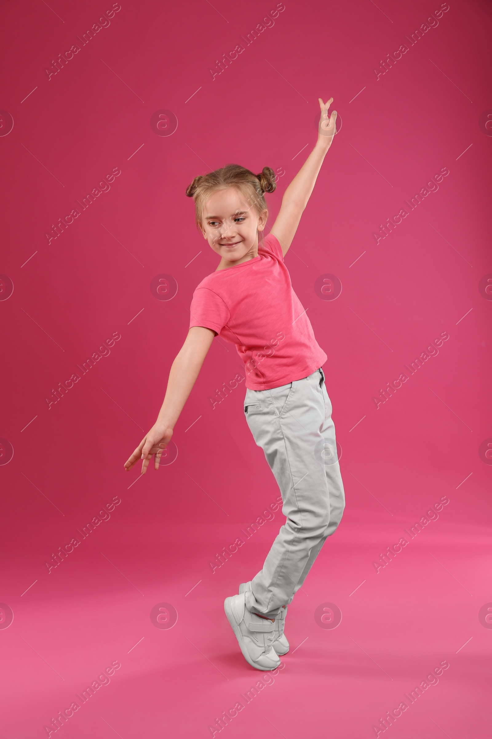 Photo of Cute little girl posing on pink background