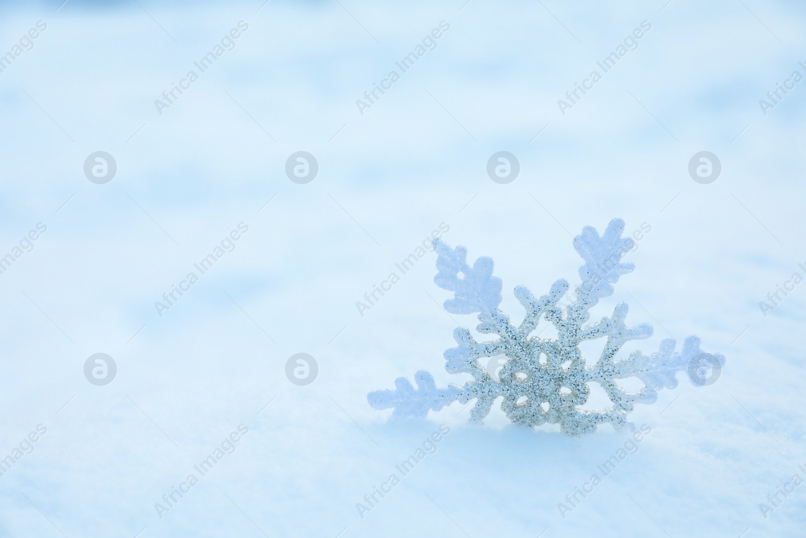 Photo of Beautiful decorative snowflake in white snow, outdoors. Space for text