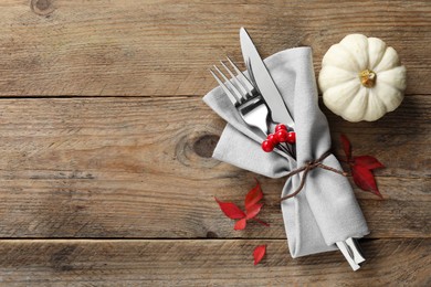 Thanksgiving table setting. Cutlery, napkin, autumn leaves and pumpkin on wooden background, flat lay with space for text