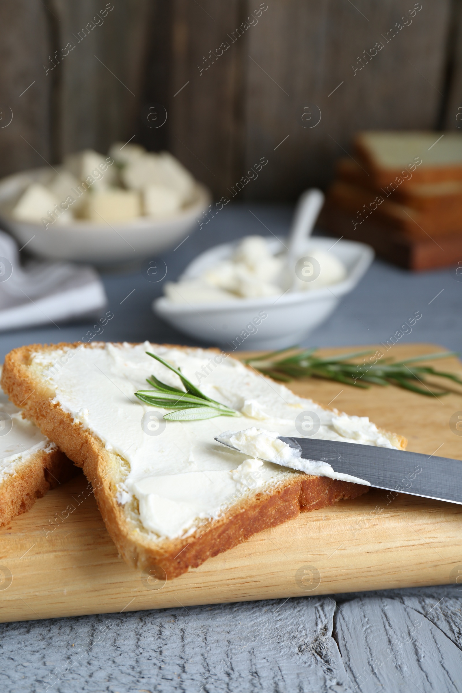 Photo of Delicious toast with tofu cream cheese and rosemary on grey wooden table, closeup