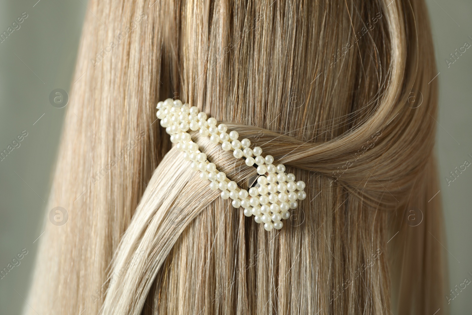 Photo of Young woman with beautiful hair clip on grey background, closeup