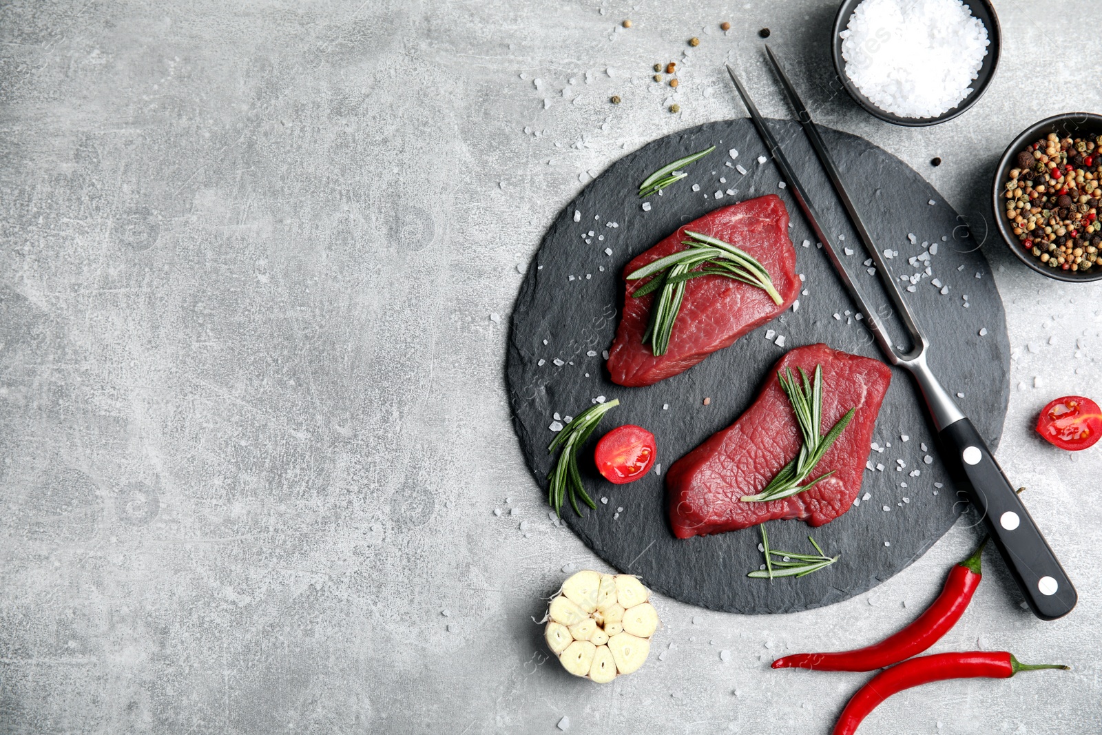 Photo of Fresh raw meat steaks and spices on light grey table, flat lay. Space for text