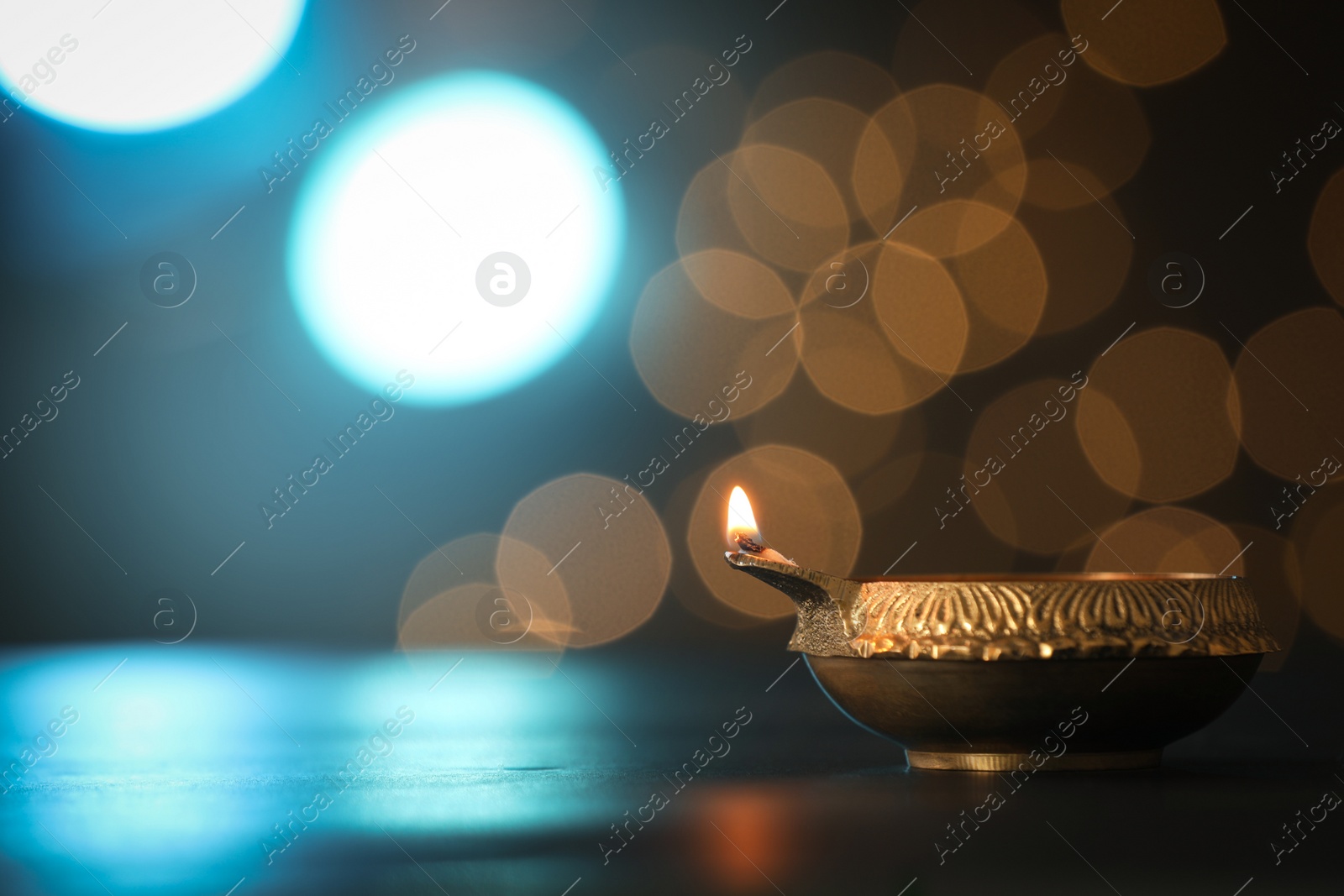 Photo of Lit diya lamp on dark table, space for text. Diwali celebration