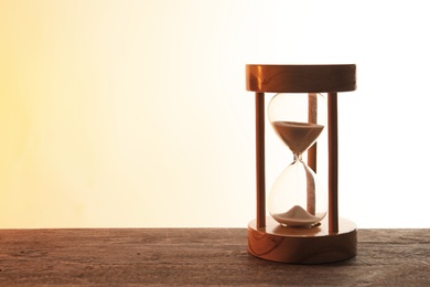 Hourglass with flowing sand on table against light background. Time management