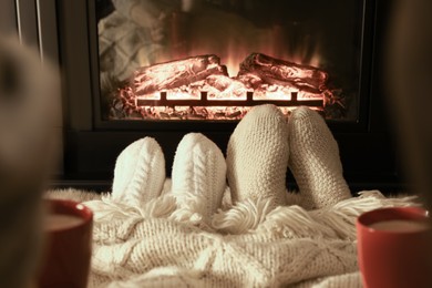 Photo of Couple in knitted socks near fireplace at home, closeup