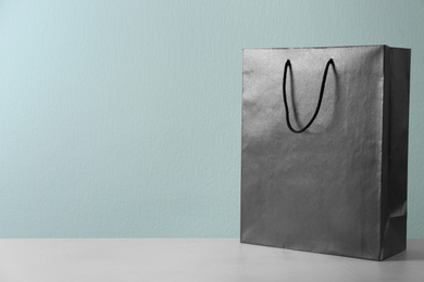 Photo of Black shopping paper bag on table against light background. Space for text