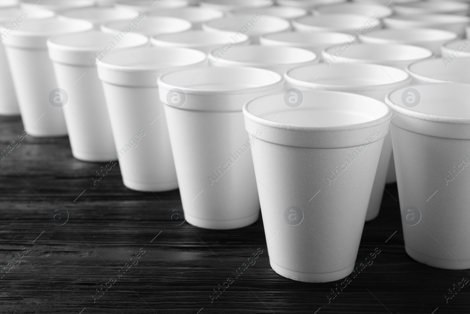 Photo of Many white styrofoam cups on black wooden table, closeup