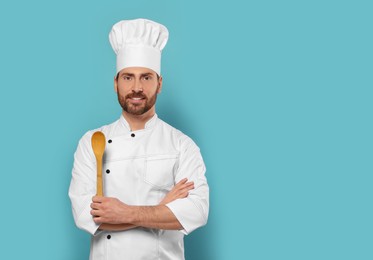Photo of Smiling mature chef with spoon on light blue background, space for text