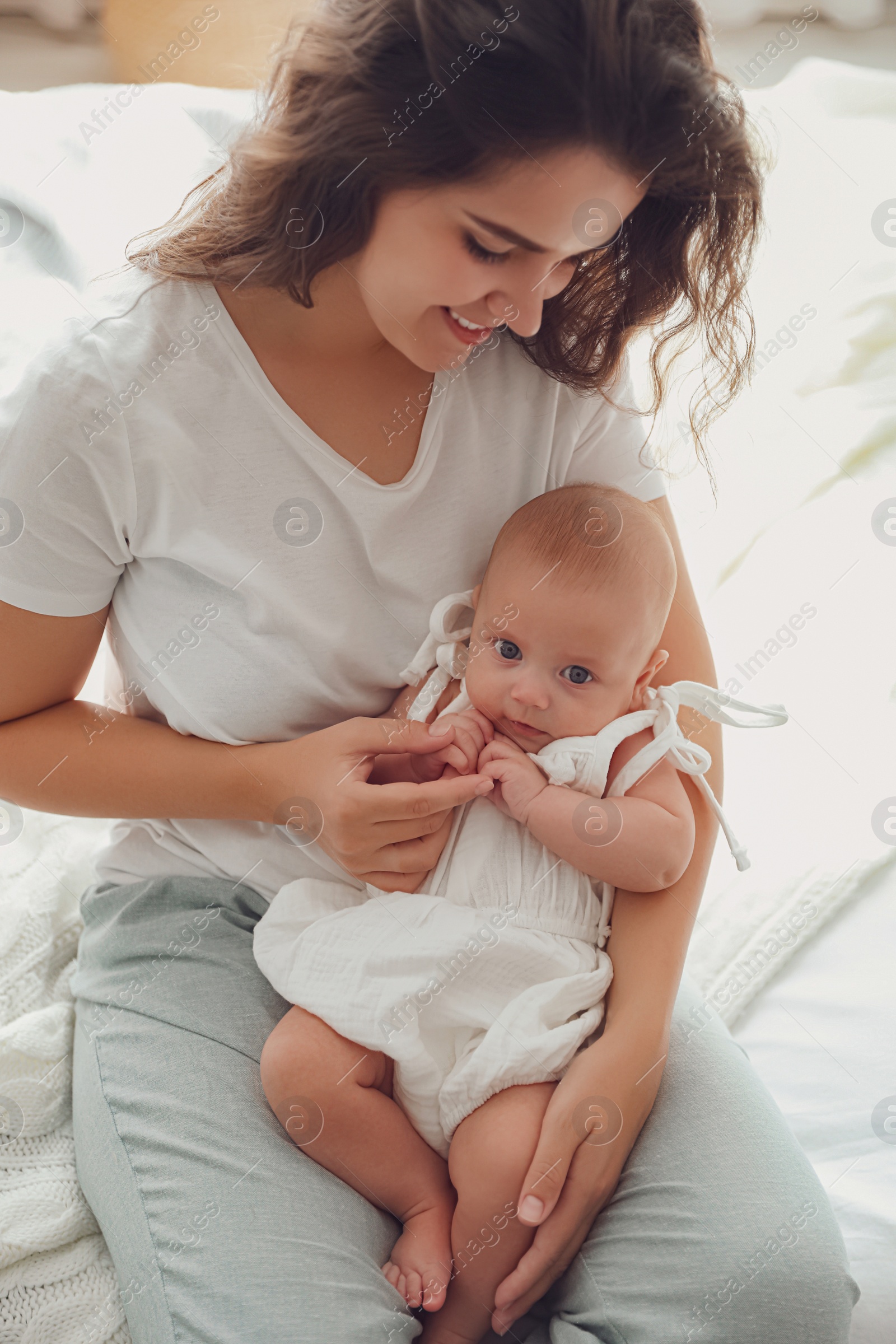 Photo of Happy young mother with her cute baby on bed at home