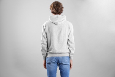 Man in hoodie sweater on light background. Space for design