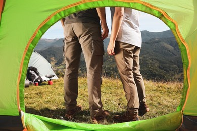 Photo of Couple in mountains on sunny day, view from camping tent