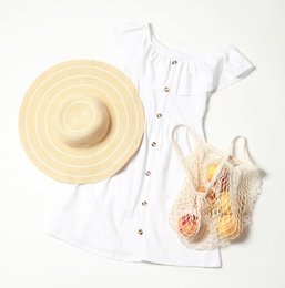 Photo of Stylish dress, hat and peaches on white background, flat lay