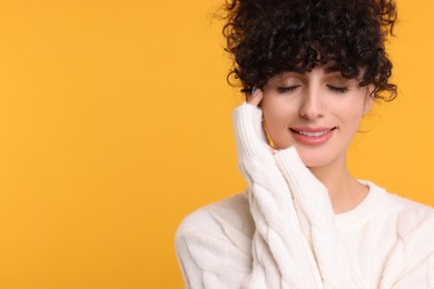 Photo of Happy young woman in stylish white sweater on yellow background, space for text