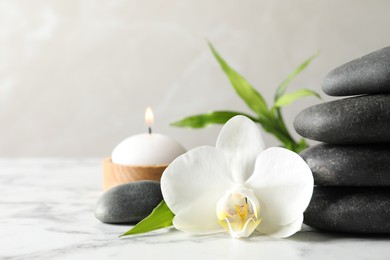 Photo of Spa stones, bamboo sprout, burning candle and beautiful orchid flower on white marble table, space for text