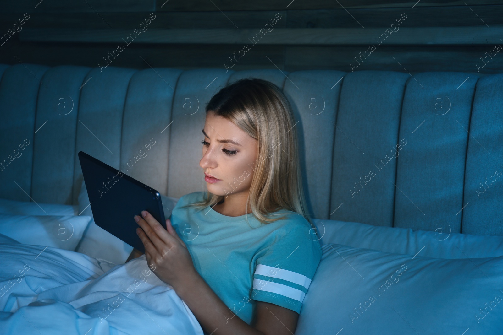 Photo of Young woman using tablet in bed at night. Sleeping disorder problem