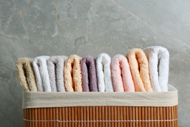 Photo of Laundry basket with clean terry towels near grey wall, closeup