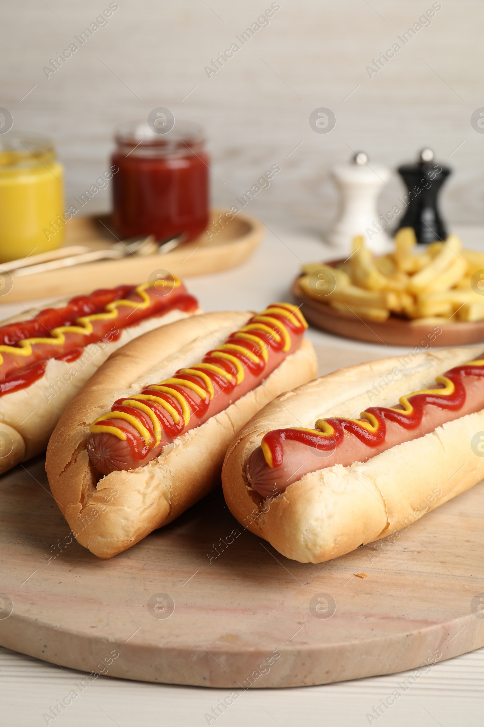 Photo of Fresh delicious hot dogs with sauces on white table