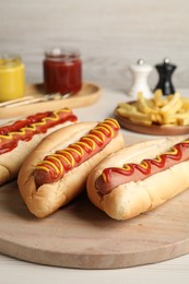 Photo of Fresh delicious hot dogs with sauces on white table