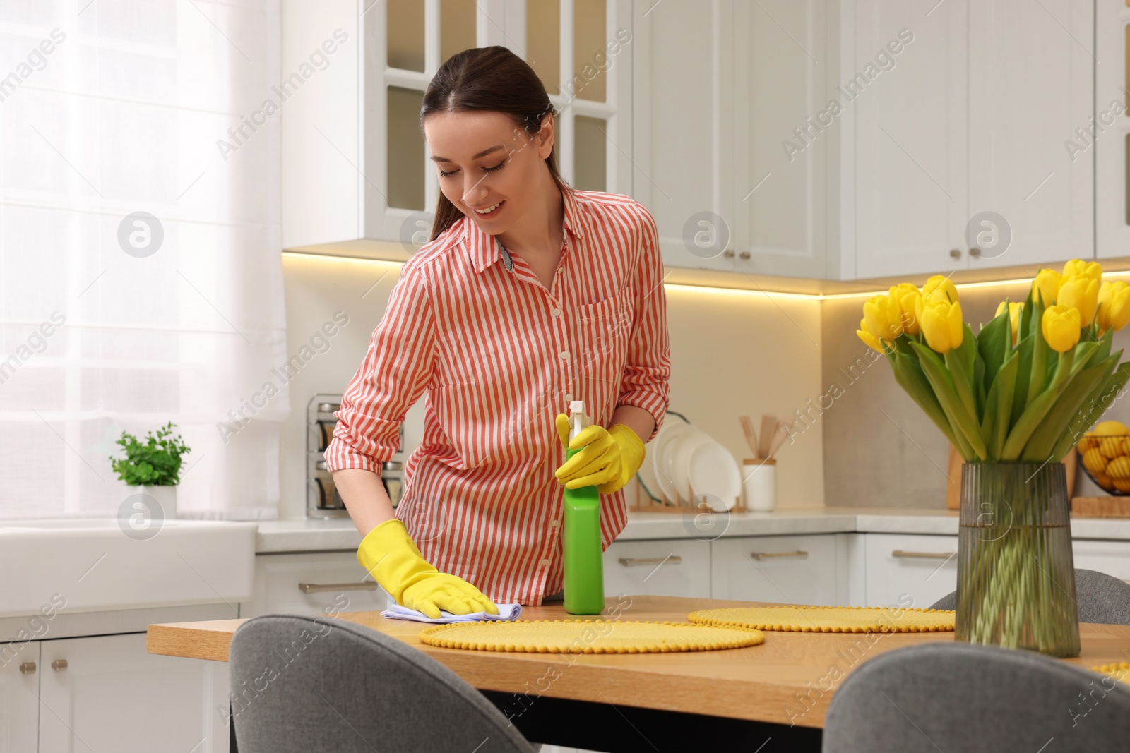 Photo of Spring cleaning. Young woman tidying up kitchen at home