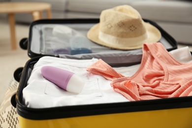 Photo of Suitcase with deodorant and clothes at home