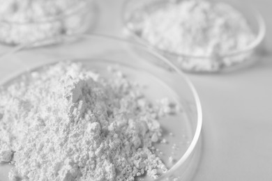 Photo of Petri dishes with calcium carbonate powder on white table, closeup