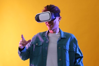Photo of Young man with virtual reality headset on yellow background
