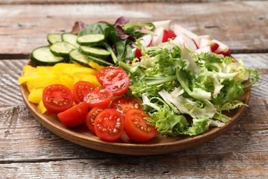 Photo of Vegetarian diet. Plate with tasty vegetables on wooden table, closeup