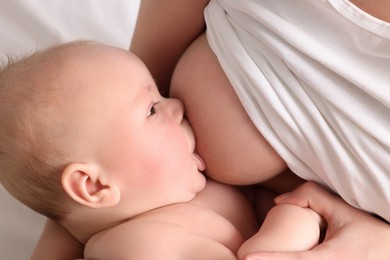 Photo of Mother breastfeeding her newborn baby on bed, closeup