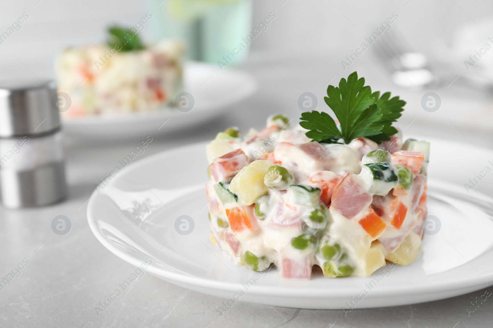 Photo of Delicious salad Olivier in plate on light table, closeup