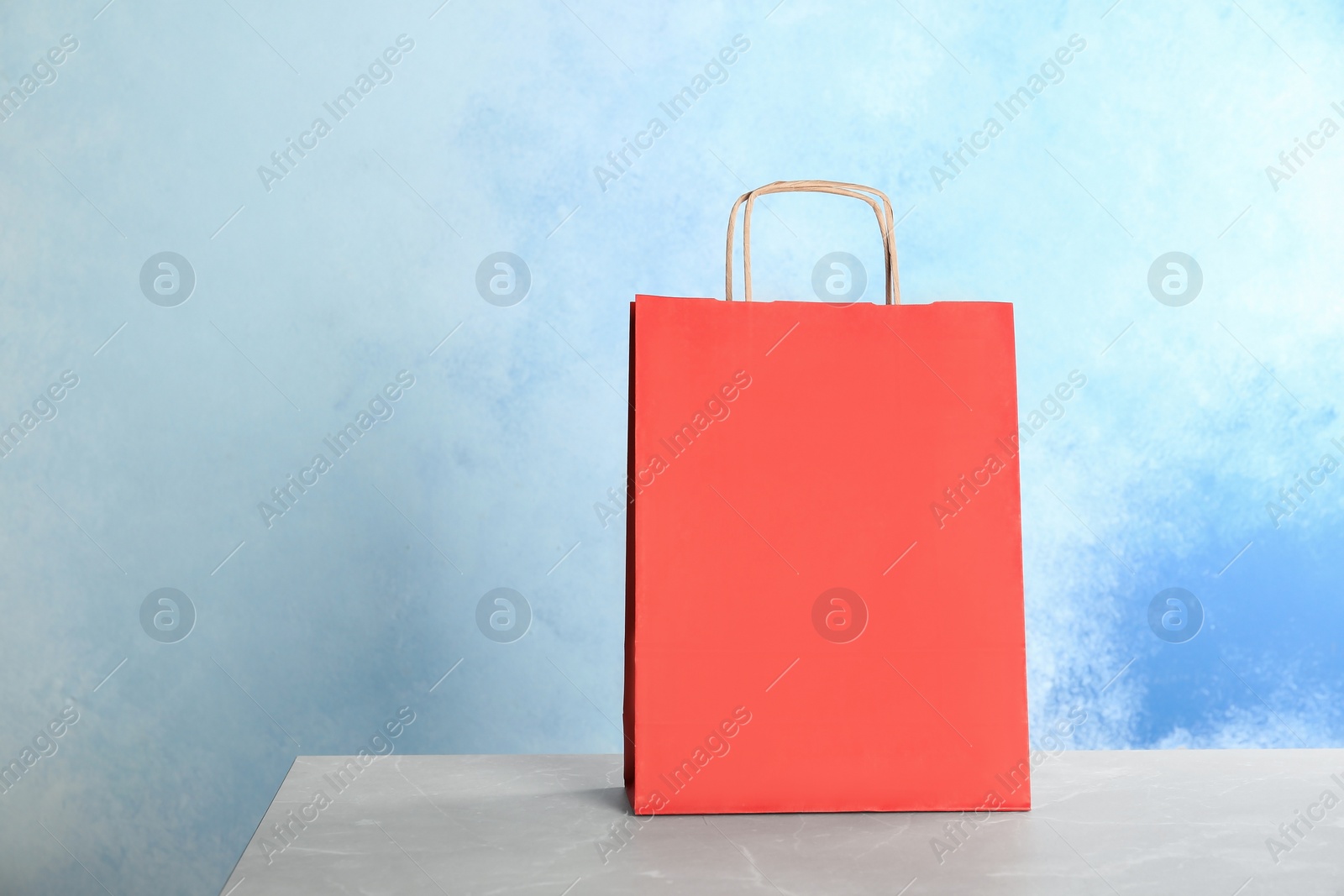 Photo of Mockup of paper shopping bag on table against color background