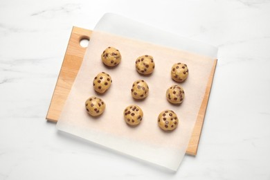 Photo of Uncooked chocolate chip cookies on white marble table, top view