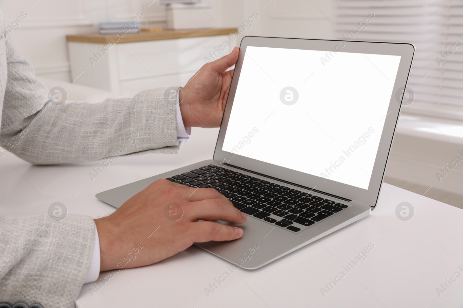 Photo of Businessman with modern laptop at white table indoors, closeup. Space for design