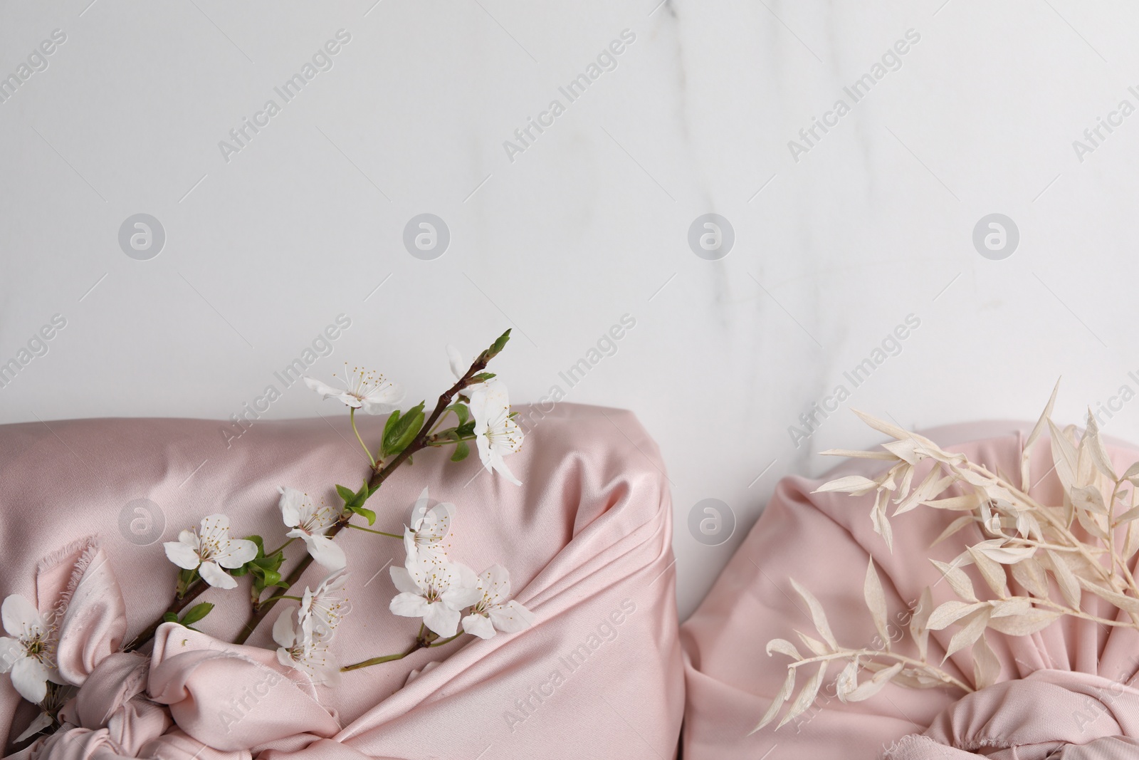 Photo of Furoshiki technique. Gifts packed in pink fabric on white marble table, flat lay. Space for text