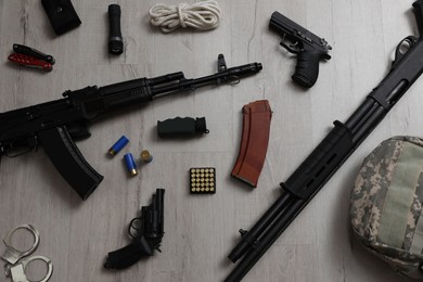 Photo of Flat lay composition with different guns and military knapsack on wooden background