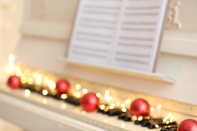 Photo of Blurred view of white piano with festive decor, closeup. Christmas music