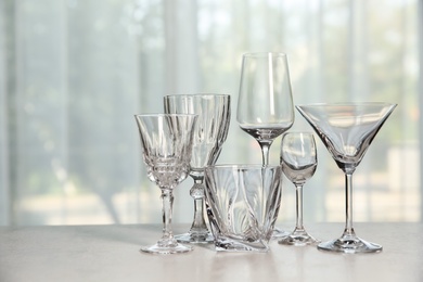 Different elegant empty glasses on grey table indoors