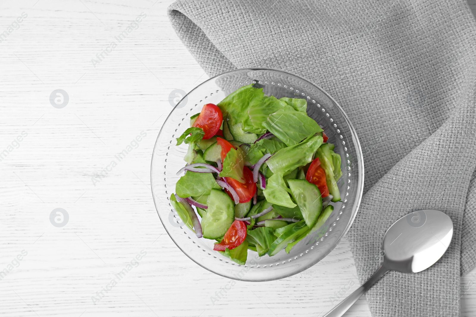 Photo of Bowl of salad with cucumber, lettuce and tomato served on white wooden table, flat lay. Space for text