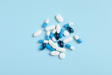 Photo of Many different pills on light blue background, flat lay