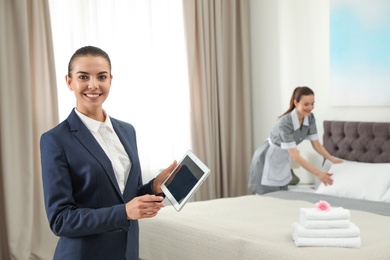 Housekeeping manager with tablet checking maid work in hotel room. Space for text