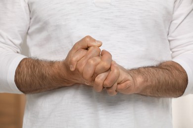 Man cracking his knuckles on blurred background, closeup. Bad habit