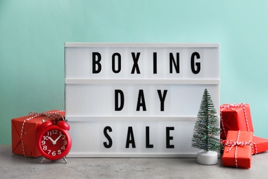 Photo of Lightbox with phrase BOXING DAY SALE and Christmas decorations on grey table
