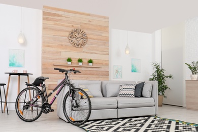 Bicycle near sofa in stylish room interior