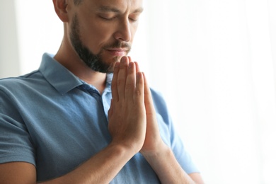 Photo of Man with hands clasped together for prayer on light background. Space for text